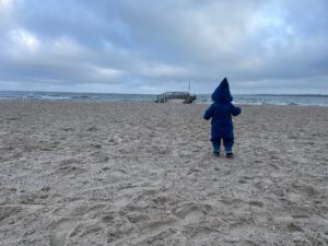 Kind am Strand, Wolken, Steg